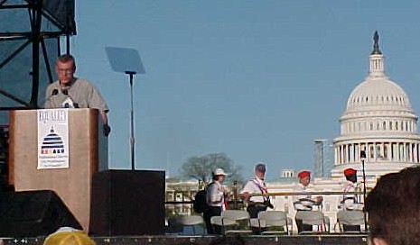 Steve stands at podium with the capitol building behind him.