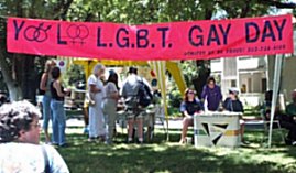 Photo: Bright red banner stretched across the park with the words Yolo county G.L.B.T. Gay Day