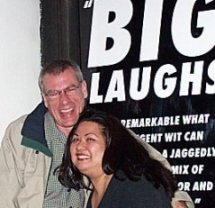 Steve and Karen Tiongson stand in front of a big sign that says HUGE LAUGHS.