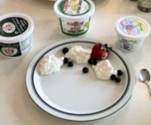 A plate with three scoops of cottage cheese and fruit