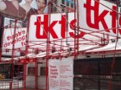 The TKTS booth in Times Square where people line up to buy discount tickets to all the shows. It consists of white banners with big red letters.