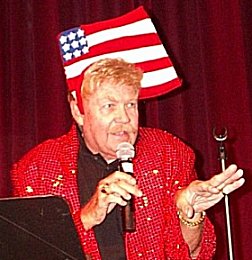 For my blind readers, this picture is Rip Taylor wearing what can only be described as an American flag on his head. It's looks like it's waving. And he's wearing a red spangled coat.