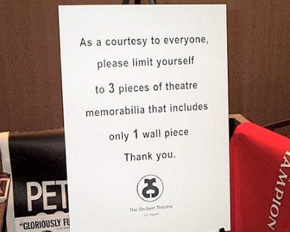 The sign says As a courtesy to everyone else, limit yourself to three pieces of theatre memorabilia...