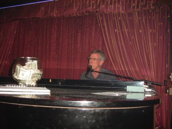 Steve Schalchlin singing in Dallas with a big tip bowl in front of him.
